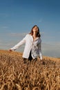 Happy young woman in a white shirt in a wheat field. Sunny day. Royalty Free Stock Photo