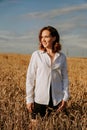 Happy young woman in a white shirt in a wheat field. Sunny day. Royalty Free Stock Photo