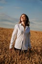 Happy young woman in a white shirt in a wheat field. Sunny day. Royalty Free Stock Photo