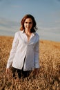 Happy young woman in a white shirt in a wheat field. Sunny day. Royalty Free Stock Photo