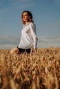 Happy young woman in a white shirt in a wheat field. Sunny day. Royalty Free Stock Photo