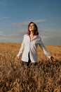 Happy young woman in a white shirt in a wheat field. Sunny day. Royalty Free Stock Photo