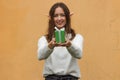 Happy young woman in white sweater with elf ears holding green gift box with bow in front of her. Christmas shopping. Royalty Free Stock Photo