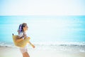 Happy young woman with beach straw bag walking on seacoast Royalty Free Stock Photo