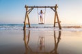 Happy young woman on wooden swing in water, beautiful blue sea Royalty Free Stock Photo