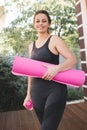 Happy young woman 25-30 year old work out at home. Smiling girl pactice fitness holding bottle of water and yoga mat. Royalty Free Stock Photo