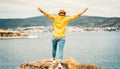 Happy young woman in a yellow shirt and hat rejoices on the seashore with a view, summer vacation and travel. Image with retro