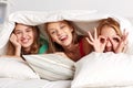 Happy young women in bed at home pajama party