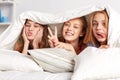 Happy young women in bed at home pajama party