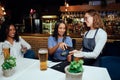 Happy young women in casual clothing paying for drinks with card machine next to waitress Royalty Free Stock Photo