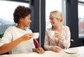 Happy young women drinking tea or coffee at cafe Royalty Free Stock Photo