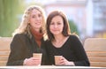 Happy young women friends drinking coffee at city street restaurant during work break. Socializing and friendship Royalty Free Stock Photo