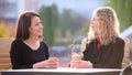 Happy young women friends drinking coffee at city street restaurant during work break. Socializing and friendship Royalty Free Stock Photo