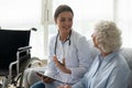 Happy young woman doctor consult disabled handicapped old grandma patient