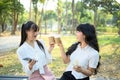 Happy young women office workers sitting on park bench and drinking coffee Royalty Free Stock Photo