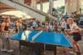 Happy young women playing ping-pong in crowd of friends at club in urban area Royalty Free Stock Photo