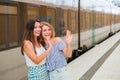 Happy young women standing on train station platform and waving their hands Royalty Free Stock Photo