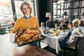 happy young woman with thanksgiving turkey for holiday dinner with family and looking