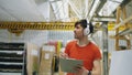 Happy young worker in industrial warehouse listening to music and dancing during work. Man in headphones have fun at Royalty Free Stock Photo