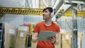 Happy young worker in industrial warehouse listening to music during work. Man in headphones have fun at workplace. Royalty Free Stock Photo