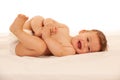 Hapy baby boy in playing on bed isolated over white