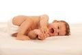 Hapy baby boy in playing on bed isolated over white