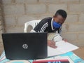 African school child wearing face mask learning using laptop.