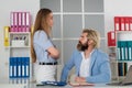 Harassment at work. Harassment with a boss touching the arm to his secretary who is sitting in his workplace at office Royalty Free Stock Photo