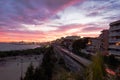 Harbor and beach of a Mediterranean city at sunset time. Dramatic pink sky. Train passing by the coast very fast. Apartment Royalty Free Stock Photo