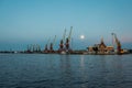 Harbor cargo cranes on eveinng sky background