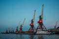 Harbor cargo cranes on evening sky background