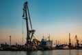 Harbor cargo cranes on evening sky background