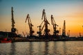 Harbor cargo cranes on sunset sky background