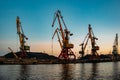 Harbor cargo cranes on sunset sky background