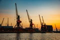 Harbor cargo cranes on sunset sky background