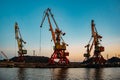 Harbor cargo cranes on sunset sky background