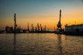 Harbor cargo cranes on sunset sky background