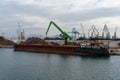 Harbor crane unloading scrap metal from a freight ship in the industrial port of Ploce