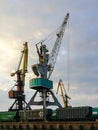 Harbor cranes with grain wagons between crane legs, seaport industry scene, grain export