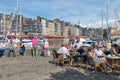 Harbor historic city Honfleur with people sitting at terrace restaurant