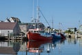 A harbor in Nova Scotia with three fishing boats tied to a dock.