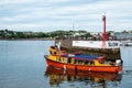 Harbor wall marked with SLOW 5 KNOTS MAX safety warning as a passenger ferry boat sails out of the harbor