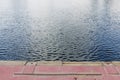 Harbor wall with two black bollards and calm harbor water Empty boat berth