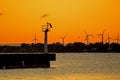 Harbour Beacon At Sunrise With Windmills In Background