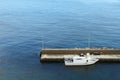 Harbour and small white fishing boat tied to the pier in the Mediterranean Sea with blue sea waters on the background. Royalty Free Stock Photo