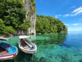 Harboured boats on crystal clear sea with rock cave background Royalty Free Stock Photo