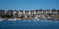 Harbourside condominium apartment housing with boats floating on blue water against blue sky