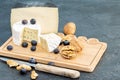 Hard cheese and blue cheese brie with some fruits on the wooden cheese board.