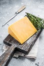 Hard cheese with knive on wooden cutting board. Parmesan. Gray background. Top view