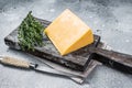 Hard cheese with knive on wooden cutting board. Parmesan. Gray background. Top view